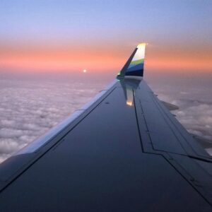 Plane wing with clouds and sunset