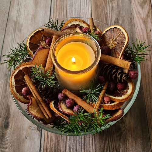 A lighted candle in a bowl of natural potpourri