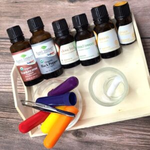 Aromatherapy inhalers and a wick on a tray with bottles of essential oil.