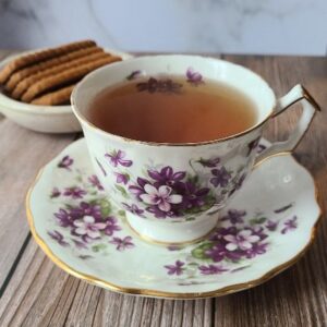 Orange Mint Tea in a porcelain tea cup with bowl of tea biscuits