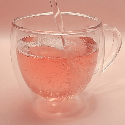Rose herbal tea pouring into a glass tea cup 