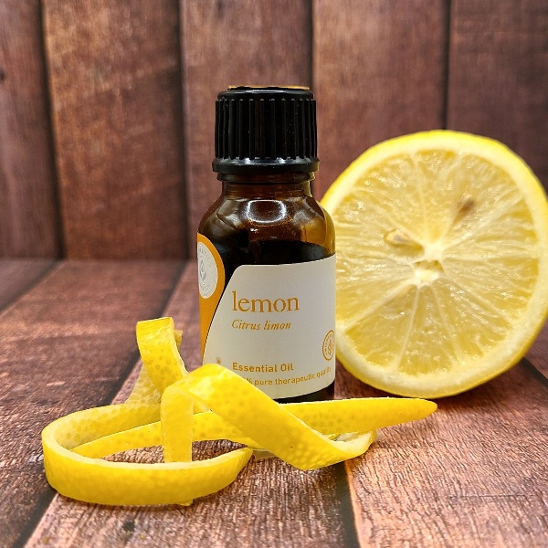 Bottle of Lemon essential oil, sliced lemon and a curl of lemon peel