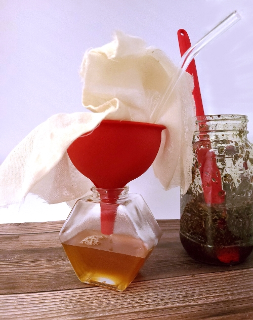 Filtering Herbal Honey into a glass honey jar