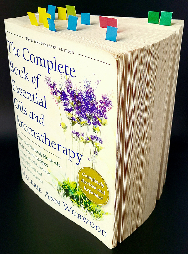 The Complete Book of Essential Oils and Aromatherapy by Valerie Ann Worwood standing.on edge with multiple colored page markers