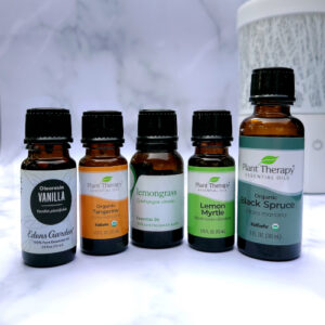 Bottles of Vanilla, Tangerine, Lemongrass, Lemon Myrtle, and Black Spruce essential oils with diffuser in background.